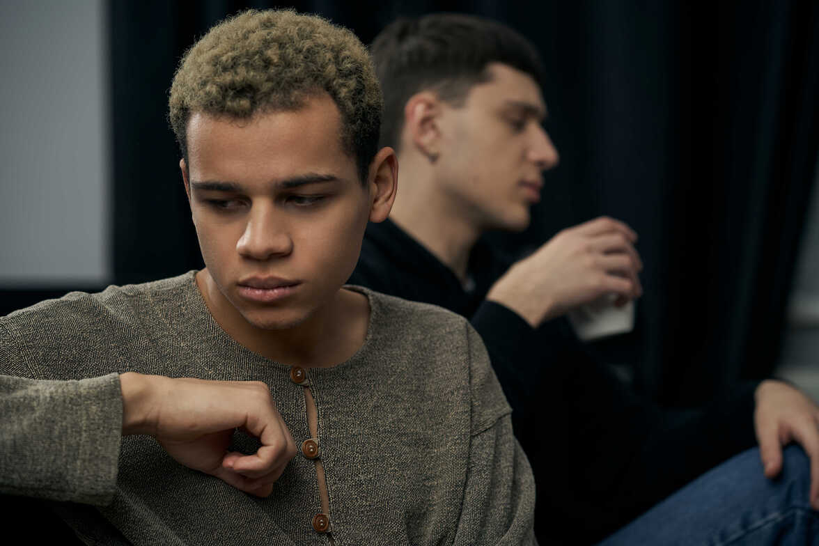 A person in a gray shirt with a gloomy expression is considering LGBTQIA individual counseling for emotional support